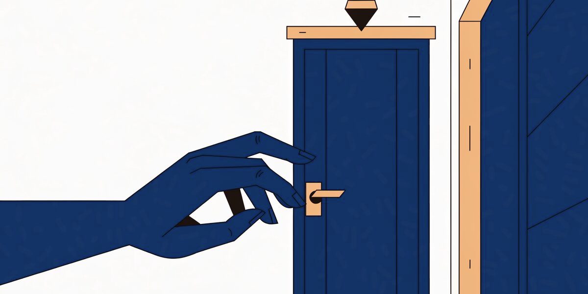 Une main s'approche de la poignée d'une porte d'appartement fermée, éclairée par une applique