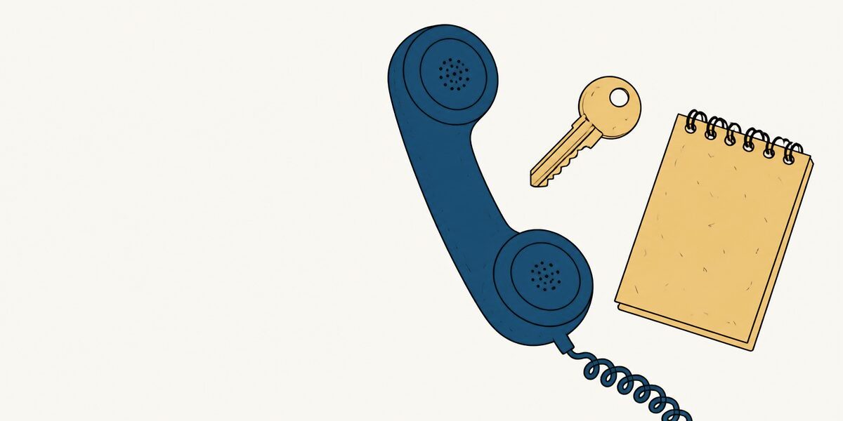 Un combiné de téléphone, une clé et un carnet à spirale posés côte à côte